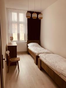 een kamer met 2 bedden, een stoel en een raam bij Apartament na Rynku in Wągrowiec