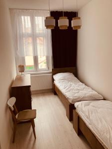 two beds in a room with a chair and a window at Apartament na Rynku in Wągrowiec