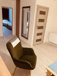 een woonkamer met een groene stoel en een spiegel bij Apartament na Rynku in Wągrowiec