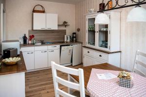 a kitchen with white cabinets and a table with a pink table cloth at FEWO Hafenblick in Lübbenau