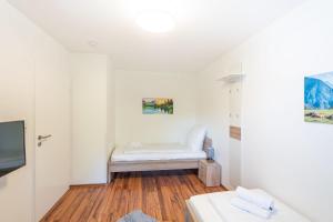 a small white room with a bed and a tv at Allgäu-Heimat in Sonthofen
