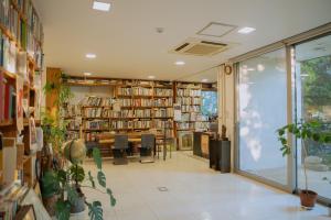 Motif No.1 Guest House في باجو: مكتبة فيها طاولة وكراسي ورفوف كتب