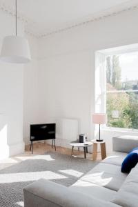 a white living room with a couch and a television at Spacious Georgian Pad - Free Parking - Walk to Bath in Bath