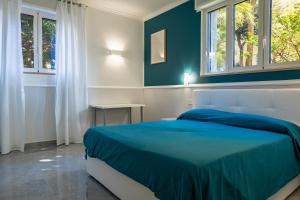 een slaapkamer met een blauw bed en 2 ramen bij RUA DE MAR PORTICI in Portici