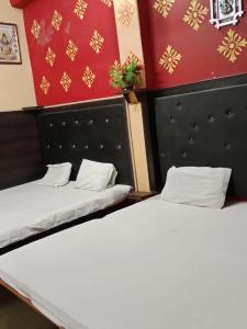 duas camas num quarto com parede vermelha e dourada em Maa Vaishno Guest House em Varanasi