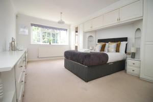 a white bedroom with a large bed and a window at Chartwell Grove (Spacious 7 BR with FREE parking) in Nottingham