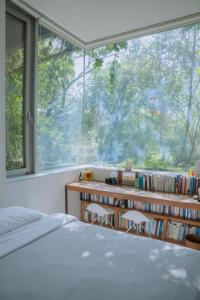 Motif No.1 Guest House في باجو: غرفة نوم مع نافذة كبيرة ومكتب مع الكتب