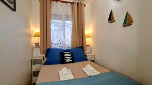 une chambre avec un lit avec des oreillers bleus et une fenêtre dans l'établissement Appartement Kallisté, Logements avec vue citadelle de Bonifacio, à Bonifacio