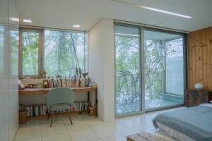 a bedroom with a desk and a bed and windows at motif1 in Paju