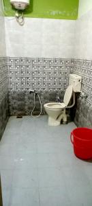 a bathroom with a toilet and a red bucket at AVAR Home syay in Virāmpattinam