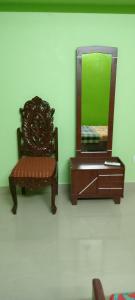 a chair and a dresser in a room with a mirror at AVAR Home syay in Virāmpattinam