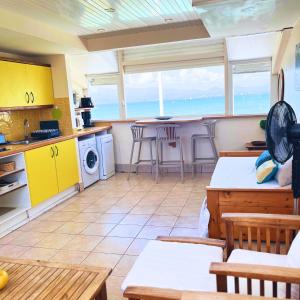een keuken met gele kasten en een tafel en stoelen bij Appartement Les Yuccas, vue sur la mer et les montagnes in Le Gosier