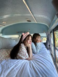 Hotel Ocean BUS Shirahama في Shioura: بنتان مستلقيتان على سرير في عربة تخييم