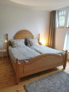 um quarto com uma grande cama de madeira com almofadas em Ferienwohnung in Anni's Ferienhaus 