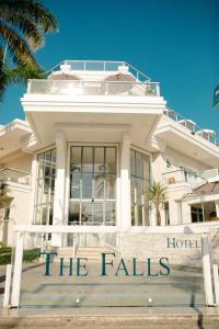 a white building with the falls sign in front of it at The Falls Hotel in Guarujá