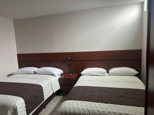 dos camas sentadas una al lado de la otra en una habitación en Hotel Caluva, en Loja