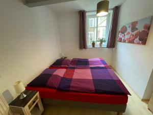 Un dormitorio con una cama colorida y una ventana en Ferienwohnung Südliche Weinstraße zwischen Wald und Reben en Klingenmünster