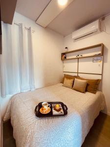 a bedroom with a bed with a tray of food on it at Loft encantador A - 8 km de Floripa in São José