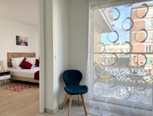 a bedroom with a blue chair in front of a window at Chic & Cozy Living - Near Heart of Paris in Clichy