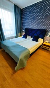 a large bed in a bedroom with a blue wall at Apartamenty Wielka Odrzańska Centrum in Szczecin