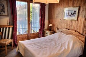 um quarto com uma cama e uma grande janela em Chalet L'isard - Chalets pour 10 Personnes 534 em Peisey-Nancroix