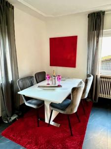 a white dining room table with chairs and a red rug at Alex in Pfaffenhausen