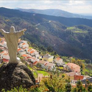 a statue of christ the redeemer on top of a mountain at Casa da Calçada - Piso 1 in Seia