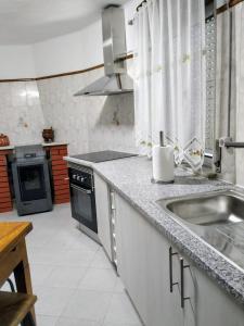 cocina con fregadero y fogones en Casa da Calçada - Piso 1, en Seia