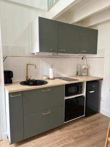 uma cozinha com armários cinzentos e um lavatório em Maisonnette plein centre 2/3p em Libourne