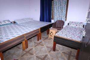 een kamer met 2 bedden en een stoel. bij HOTEL SHIVKRIPA AND RESTAURANT in Dharāsu