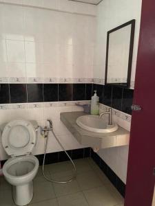 a bathroom with a toilet and a sink and a mirror at Cuti Cuti apartment Glory Beach in Port Dickson