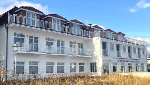 ein weißes Gebäude mit Balkon darüber in der Unterkunft Strandhotel Dünenhaus in Juliusruh