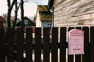 een roze deur aan een hek naast een huis bij Kalnciema kvartāla Kuldīgas rezidence in Kuldīga