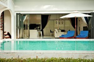 a pool with two blue chairs and an umbrella at Menara - 3 BR Private Pool Villa - Moroccan Inspired - Bangtao Beach in Phuket