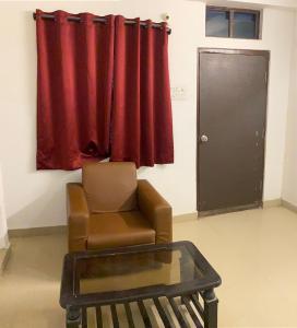 a living room with a chair and a red curtain at Hotel Fortune Heights in Hyderabad