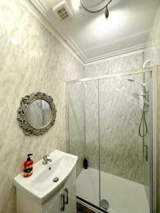 uma casa de banho com um lavatório, um chuveiro e um espelho. em Ameliafield Cottage, Prestwick em Prestwick
