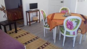 a dining room with a table and chairs and a television at Dar Fati Roses in Aït Imouni