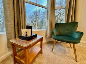 una sala de estar con una silla verde y una mesa en Gwydyr Hotel, en Betws-y-coed