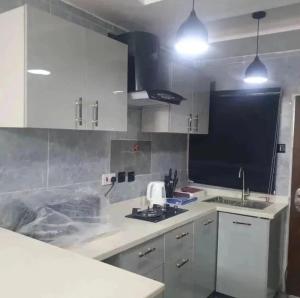 a kitchen with white cabinets and a sink at Supreme Apartments in Ibadan