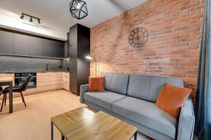 uma sala de estar com um sofá e uma parede de tijolos em Downtown Apartments DOKI Living - Foodhall & Parking em Gdansk