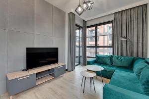 a living room with a blue couch and a flat screen tv at Downtown Apartments DOKI Living & Foodhall in Gdańsk