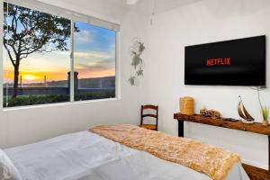 a bedroom with a bed and a tv on a wall at 'Sunsets Over Catalina' - An Insider's Secret Hideaway with an Ocean View! in Dana Point