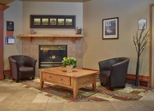 a living room with a table and two chairs and a fireplace at Neighbourhood Inn Hotels in Bonnyville in Bonnyville