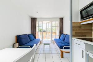 sala de estar con sofás azules y balcón en Résidence Port Bourgenay - maeva Home - Appartement 2 Pièces 5 Personnes - 64, en Talmont