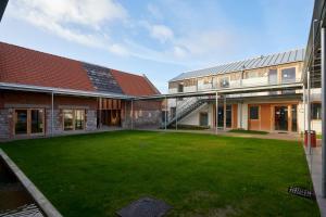 un edificio con un patio con césped verde en La Ferme Des Ailleurs en Arleux-du-Nord