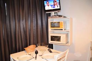 une table à manger avec un four micro-ondes et une télévision dans l'établissement Résidence Caron - Studio pour 2 Personnes 064, aux Menuires