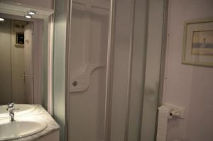 La salle de bains blanche est pourvue d'un lavabo et d'une douche. dans l'établissement Résidence Caron - Studio pour 2 Personnes 064, aux Menuires