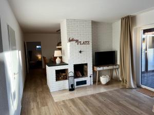 uma sala de estar com uma lareira de tijolos brancos em Appartement „Zum Weißen Hahn“ em Bad Zwischenahn