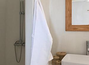 Stunning Antiparos Villa 3 Bedrooms Villa Kamino Breathtaking Sea Views في أنديباروس: منشفه بيضاء معلقه في الحمام بجانب المغسله