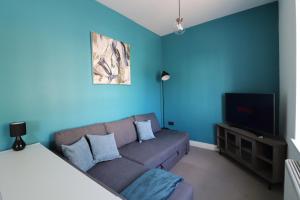 a living room with a couch and a tv at The Windsor Club Apartment in Leamington Spa